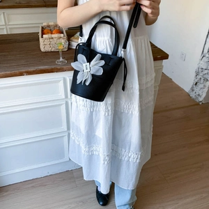 Macro detail of black lychee grain bucket bag with a decorative white chiffon flower charm
