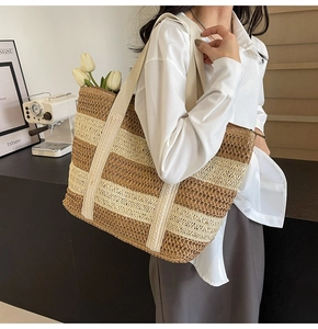 Detail of striped straw tote bag showing woven texture and side shoulder strap