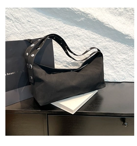 Close-up of black canvas underarm bag with silver rivet studs on the shoulder strap