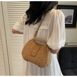 Detail of hand-woven straw crossbody bag featuring a leather patch and gold metal turn-lock