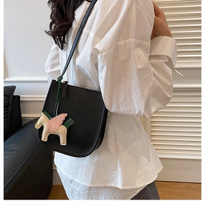 Detail of black lychee leather bucket bag with cute pegasus pendant and shoulder strap