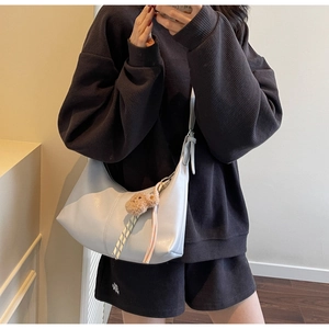 Light blue crescent shoulder bag with bear pendant and woven strap shown on model