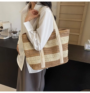 Detail of a large straw tote bag with brown and beige stripes and reinforced woven handles