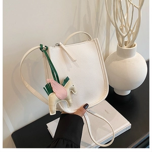 Close-up of white lychee leather bucket bag with colorful Pegasus horse charm detail