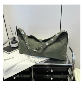 Detail of olive green suede shoulder bag with large silver metal rivets on the wide strap