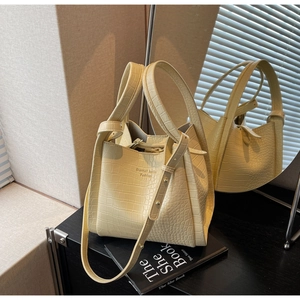 Detail of beige crocodile texture leather bag with brand lettering and adjustable strap