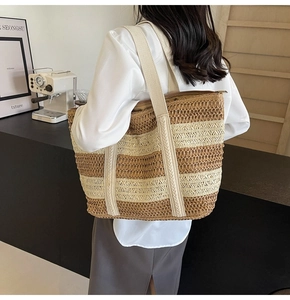 Detail of large straw tote bag with beige and brown stripes and fabric shoulder strap