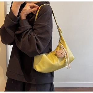 Detail of yellow leather shoulder bag featuring a cute plush bear and rope charm
