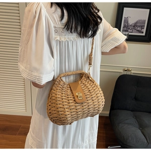 Close-up of the vintage woven straw saddle bag with a brown leather strap and gold buckle