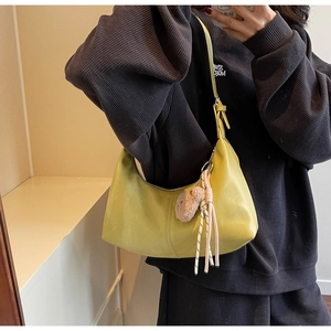 Close-up of lemon yellow faux leather underarm bag with cute brown plush bear pendant