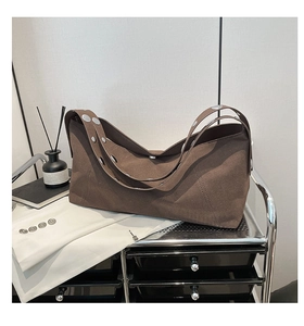 Detail of brown matte leather crossbody bag featuring silver metal rivets and a retro design