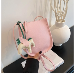 Detail of pink lychee leather mini bucket bag with a cute pegasus charm accessory