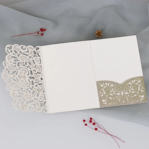 Detail of laser-cut floral lace wedding invitation with a gold glitter pocket insert