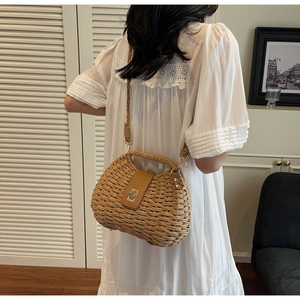 Detail of woven straw bag with brown leather flap and metal twist lock for vacation