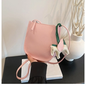 Detail of pink lychee leather bucket bag with horse charm and zip closure