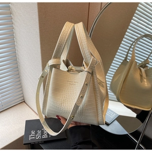 Detail of cream white crocodile pattern bucket bag with handles and detachable strap