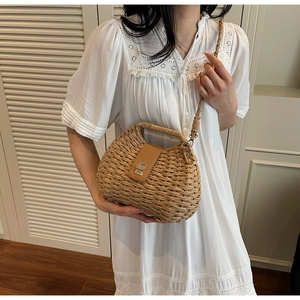 Close-up of handwoven straw crossbody bag with metal twist lock and texture details