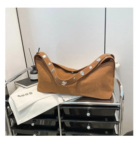 Detail of caramel suede shoulder bag featuring large silver metallic eyelet hardware