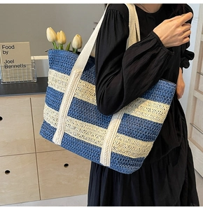 Detail of blue and beige striped straw tote bag with braided handles and summer vibe