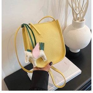 Detail of yellow lychee texture leather bucket bag with cute pegasus charm accessory