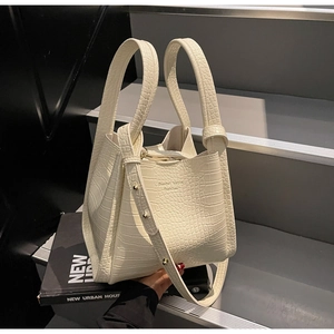 Detail of cream crocodile embossed handbag with thin shoulder strap and round handles