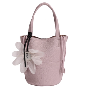 Close-up of pink pebbled leather bucket bag with silk flower charm and logo detail