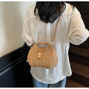 Detail of woven straw crossbody bag with brown leather clasp and gold metallic lock