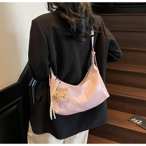 Detail of pink crescent moon shoulder bag with brown plush bear charm and woven lanyard