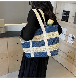 Close-up of a blue and white striped straw tote bag featuring wide woven shoulder straps