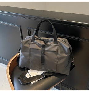 Detail of grey waterproof travel bag on chair showing handle and adjustable strap