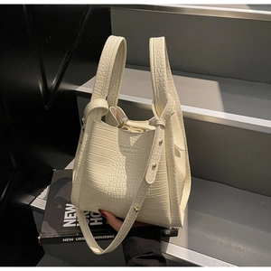 Macro detail of cream crocodile-embossed leather bucket bag with wide double handles