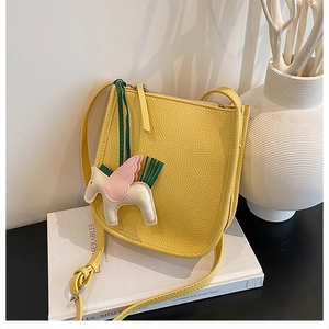 Detail of yellow lychee leather bucket bag with a cute pegasus horse charm attachment