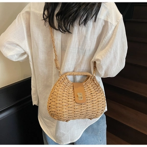 Detail of hand-woven straw crossbody bag with leather flap and gold twist lock clasp