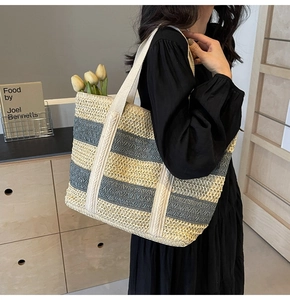 Detail of contrast color woven straw tote bag with textured shoulder strap on model