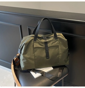 Detail of army green travel bag with black handles and metal buckles on a leather seat