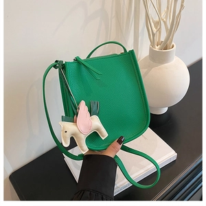Detail of green litchi texture leather crossbody bag featuring a white pony charm