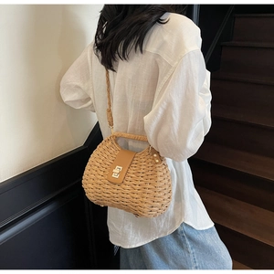 Detail of hand-woven straw crossbody bag featuring leather strap and gold metal turn-lock