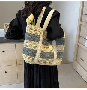 Detail of the woven texture and beige-blue stripes on a large straw beach tote bag