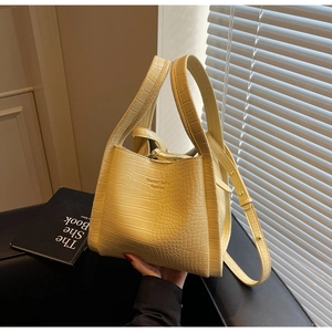Detail of yellow crocodile pattern bucket bag showing textured leather and handle