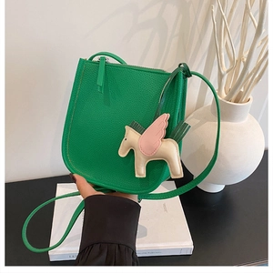 Detail of green lychee leather bucket bag with pink and white Pegasus charm