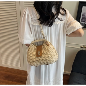 Detail of woven straw bag featuring a brown leather strap and golden metal twist lock