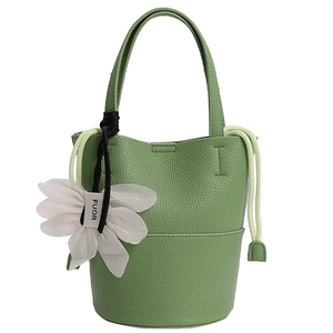 Detail of green lychee leather bucket bag featuring drawstring and white flower charm