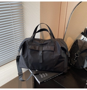 Close-up of black large capacity travel bag featuring reinforced handles and adjustable strap