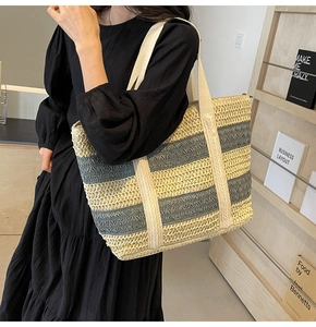 Close-up of a large striped straw tote bag with beige and dark grey woven patterns