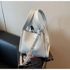 Detailed view of light blue crocodile pattern leather bucket bag with top handles