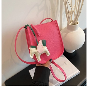 Detail of rose pink lychee leather bucket bag with a colorful leather Pegasus charm accessory