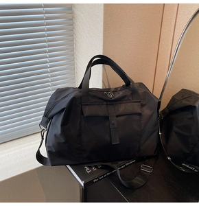 Close-up of black waterproof nylon travel bag with dual handles and detachable shoulder strap