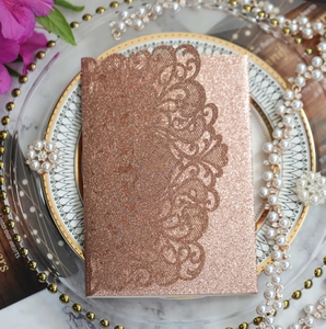 Detail of rose gold laser cut wedding invitation with glitter finish and floral lace