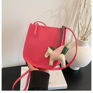 Close-up of pink leather bucket bag featuring a Pegasus horse charm and litchi texture