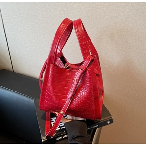 Detailed macro view of red crocodile-pattern leather bag with dual handles and logo